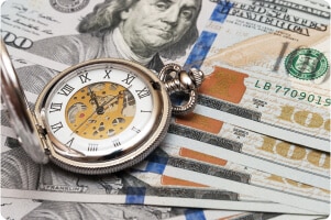 A clock lying on top of money